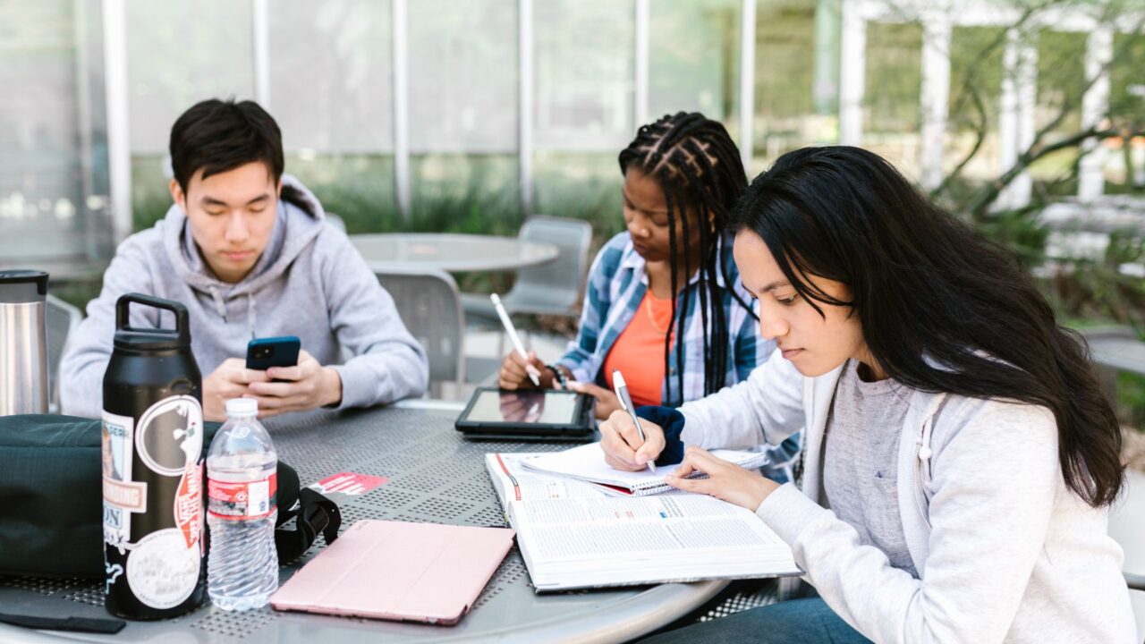 大学生たちが集まってテーブルで勉強している様子